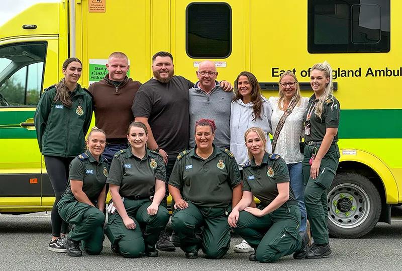 Team of individuals standing in front of a stationary ambulance